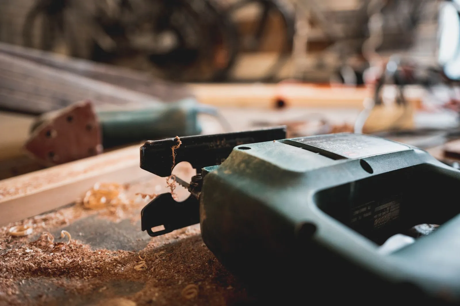 Detailed view of a jigsaw and wood shavings on a workshop table.